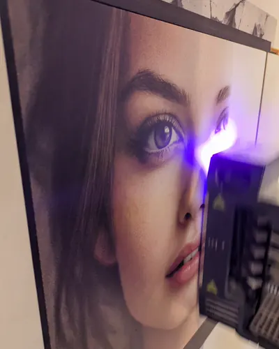 Bedruckte Platte mit dem Porträt einer jungen Frau, daneben der Druckkopf mit violett leuchtender Trocknerlampe.