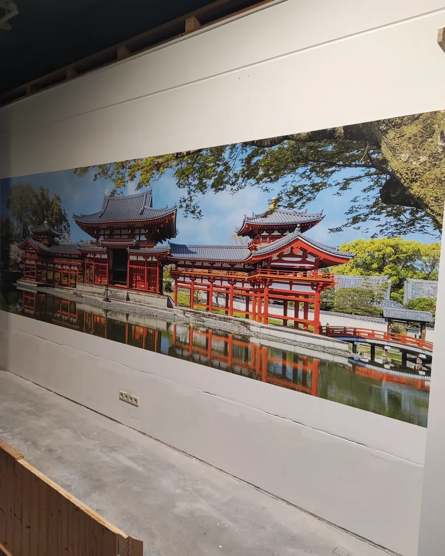 Über die gesamte Wandbreite gedrucktes Panorama einer roten japanischen Tempelanlage, die sich in einem Teich spiegelt.