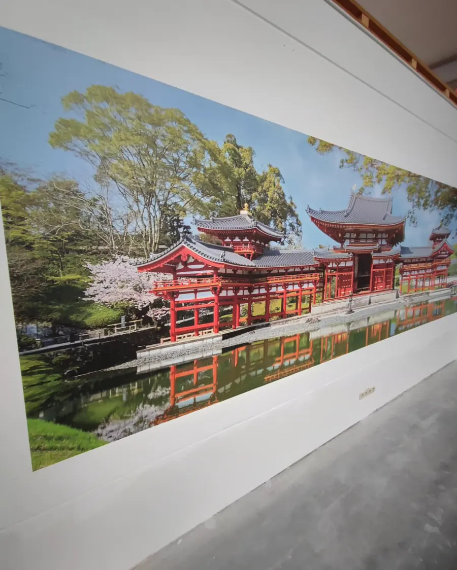 Dieselbe japanische Tempelanlage aus flachem Winkel fotografiert; das Panorama läuft über die gesamte Wand bis in den Hintergrund.